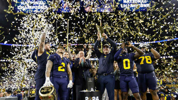 Michigan head coach Jim Harbaugh lifts up the trophy as players and coaches celebrate on stage after the 34-13 win over Washington to take the national championship game at NRG Stadium in Houston on Monday, Jan. 8, 2024.  