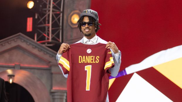 Jayden Daniels holds up his Washington Commanders jersey at the 2024 NFL draft.