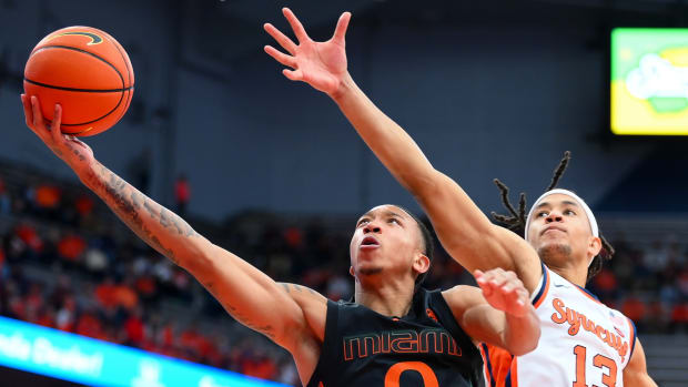 Matthew Cleveland (0) shoots the ball against the defense of Syracuse Orange forward Benny Williams (13)