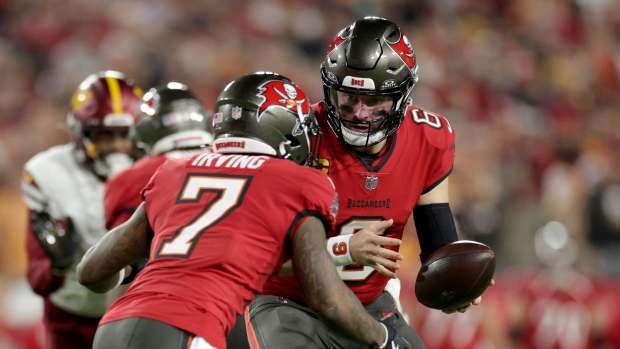 Jan 12, 2025; Tampa, Florida, USA; Tampa Bay Buccaneers quarterback Baker Mayfield (6) hands off to running back Bucky Irving (7) during the first quarter of an NFC Wild Card playoff against the Washington Commanders at Raymond James Stadium.