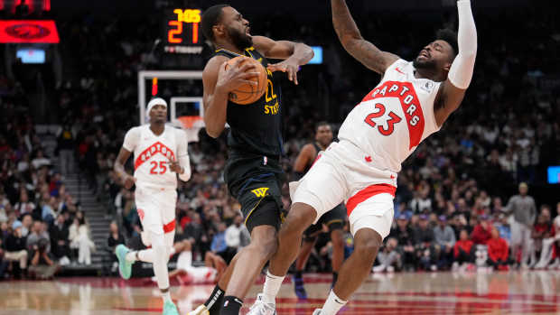 Jan 13, 2025; Toronto, Ontario, CAN; Toronto Raptors guard Jamal Shead (23) gets knocked over after colliding with Golden State Warriors forward Andrew Wiggins (22) during the second half at Scotiabank Arena. Mandatory Credit: John E. Sokolowski-Imagn Images