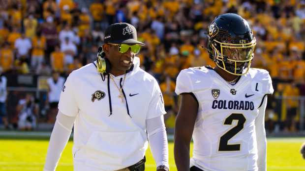 Colorado Buffaloes head coach Deion Sanders talks to quarterback Shedeur Sanders during a game against the Arizona State Sun Devils.