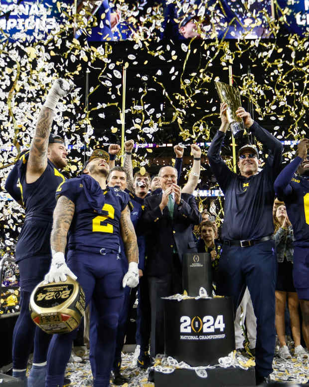 Michigan head coach Jim Harbaugh lifts up the trophy as players and coaches celebrate on stage after the 34-13 win over Washington to take the national championship game at NRG Stadium in Houston on Monday, Jan. 8, 2024.  