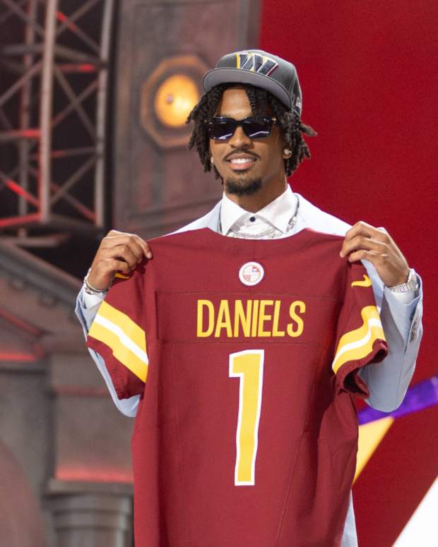 Jayden Daniels holds up his Washington Commanders jersey at the 2024 NFL draft.
