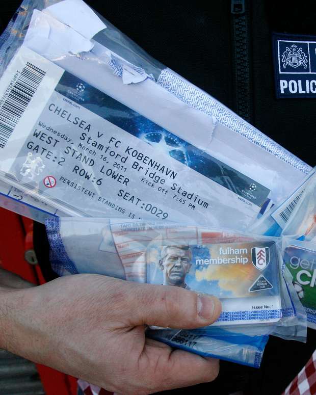 A police officer poses for photographs with English Premier League soccer club membership cards and UEFA Champions League match tickets recovered from a suspected ticket tout, during a search at the address of a furniture shop