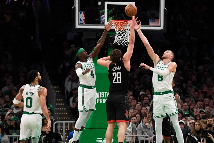 Jan 13, 2024; Boston, Massachusetts, USA; Boston Celtics guard Jrue Holiday (4) and center Kristaps Porzingis (8) and Houston Rockets center Alperen Sengun (28) battle for a rebound during the first half at TD Garden.