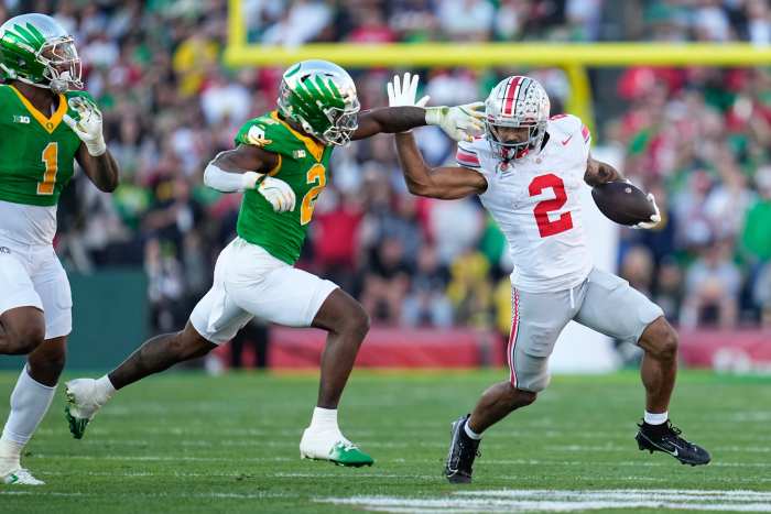 Ohio State wide receiver Emeka Egbuka brushes off Oregon Ducks tackler in College Football Playoff Game.