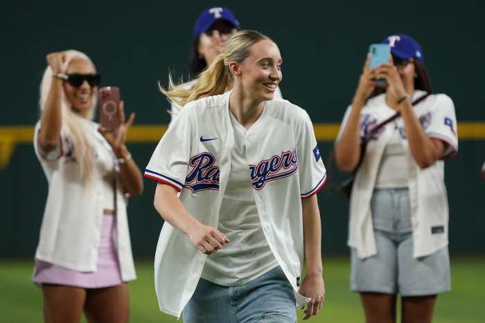 Dallas Wings point guard Paige Bueckers reacts after throwing out the first pitch, with her teammates in the background prior to game between the Texas Rangers and the Kansas City Royals at Globe Life Field.