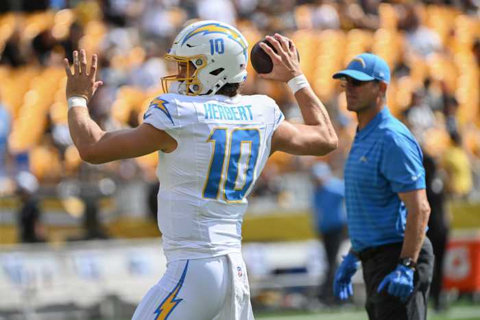 Los Angeles Chargers quarterback Justin Herbert (10) works out as head coach Jim Harbaugh looks on before a game against the Pittsburgh Steelers at Acrisure Stadium.