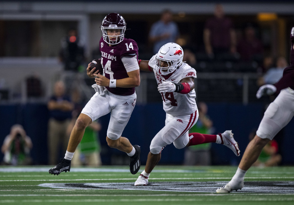 Texas A&M Aggies quarterback Max Johnson (14) eludes the rush of Arkansas Razorbacks defensive lineman Jordan Domineck (14) during the second half at AT&T Stadium. Mandatory Credit: Jerome Miron-USA TODAY Sports