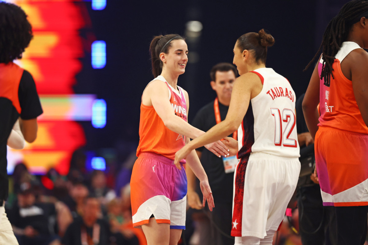 Team WNBA guard Caitlin Clark (22) shakes hands before the game with USA Women's National Team guard Diana Taurasi (12) at Footprint Center.