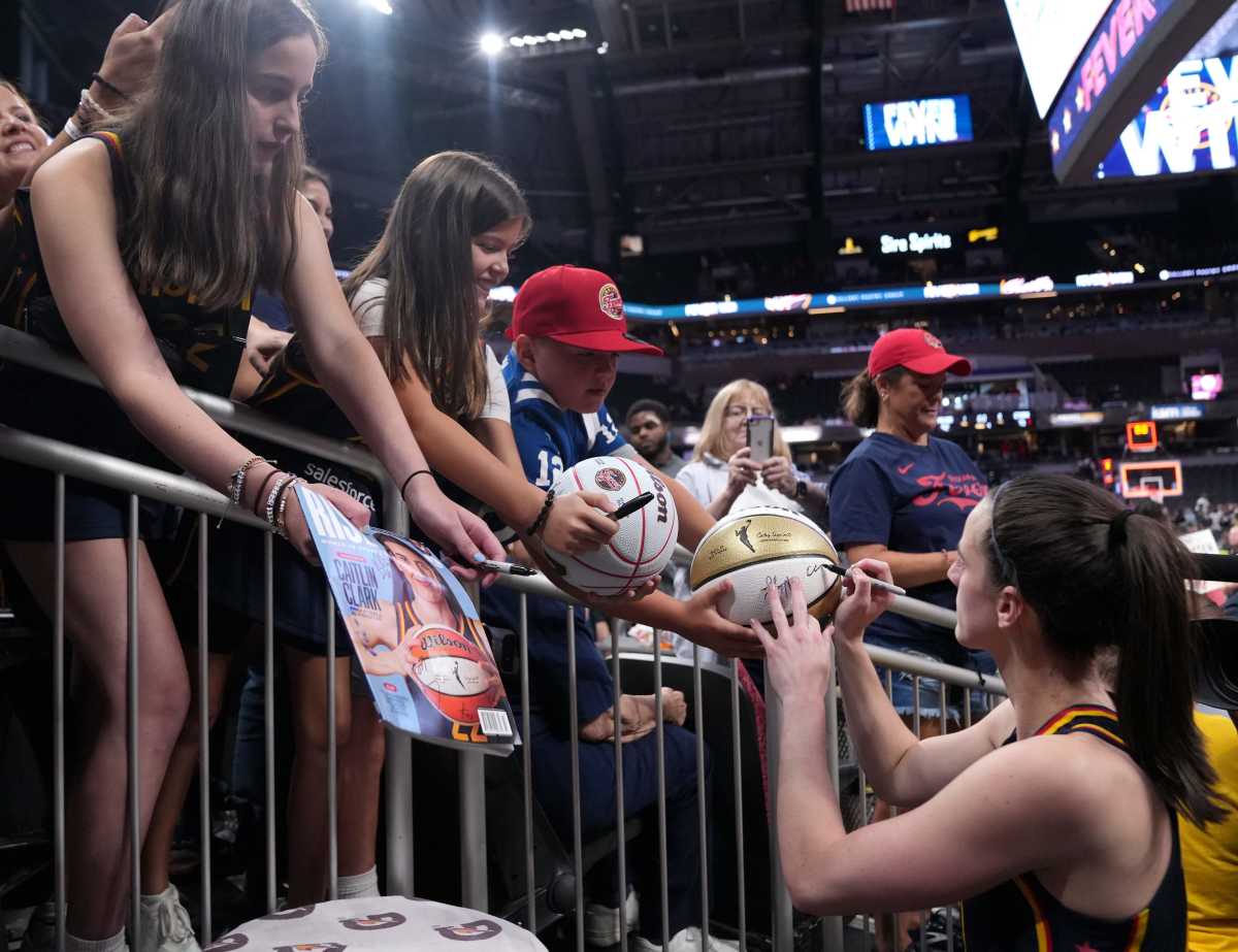 Indiana Fever guard Caitlin Clark (22) signs a basketball for a fan following a game against the Seattle Storm on Sunday, Aug. 18, 2024, at Gainbridge Fieldhouse in Indianapolis. The Fever defeated the Storm 92-75.