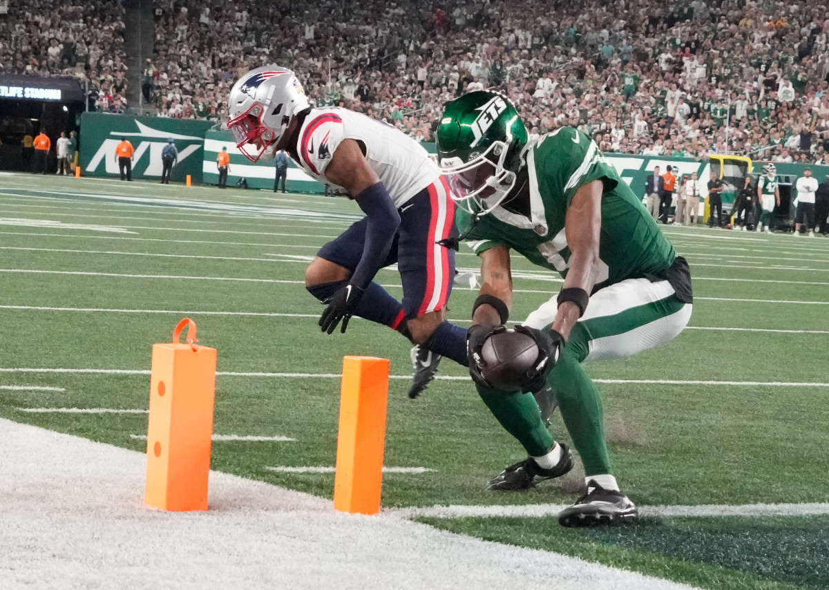 Sep 19, 2024; East Rutherford, New Jersey, USA; New York Jets wide receiver Garrett Wilson (5) scores a 3rd quarter touchdown in front of New England Patriots cornerback Christian Gonzalez (0) at MetLife Stadium.