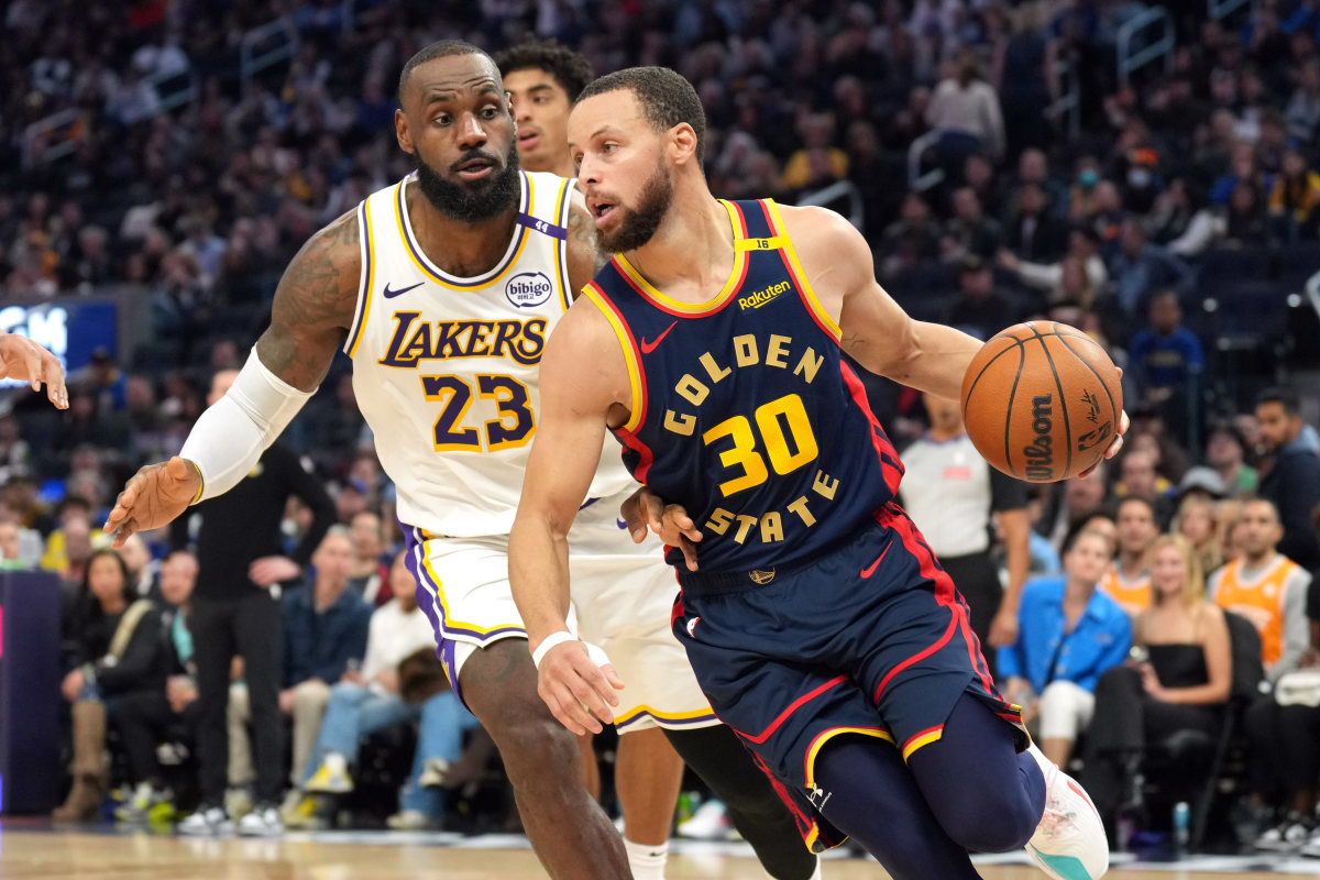 Golden State Warriors guard Stephen Curry dribbles against Los Angeles Lakers forward LeBron James.