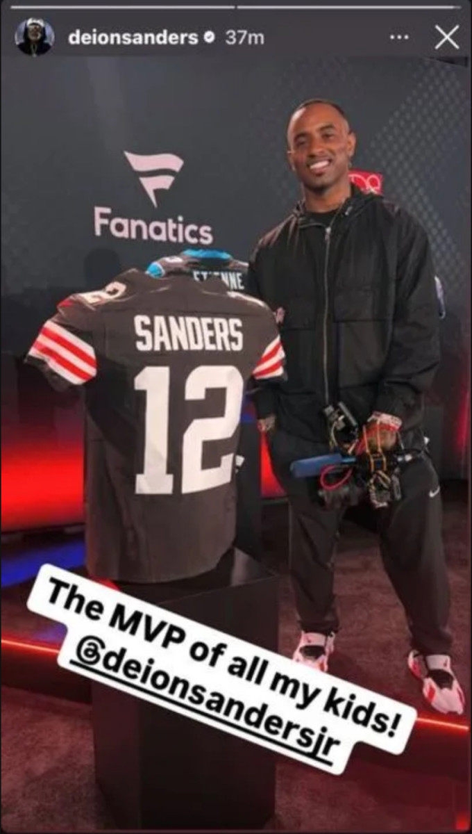 Deion Sanders Jr. standing with Shedeur’s newest Cleveland jersey.