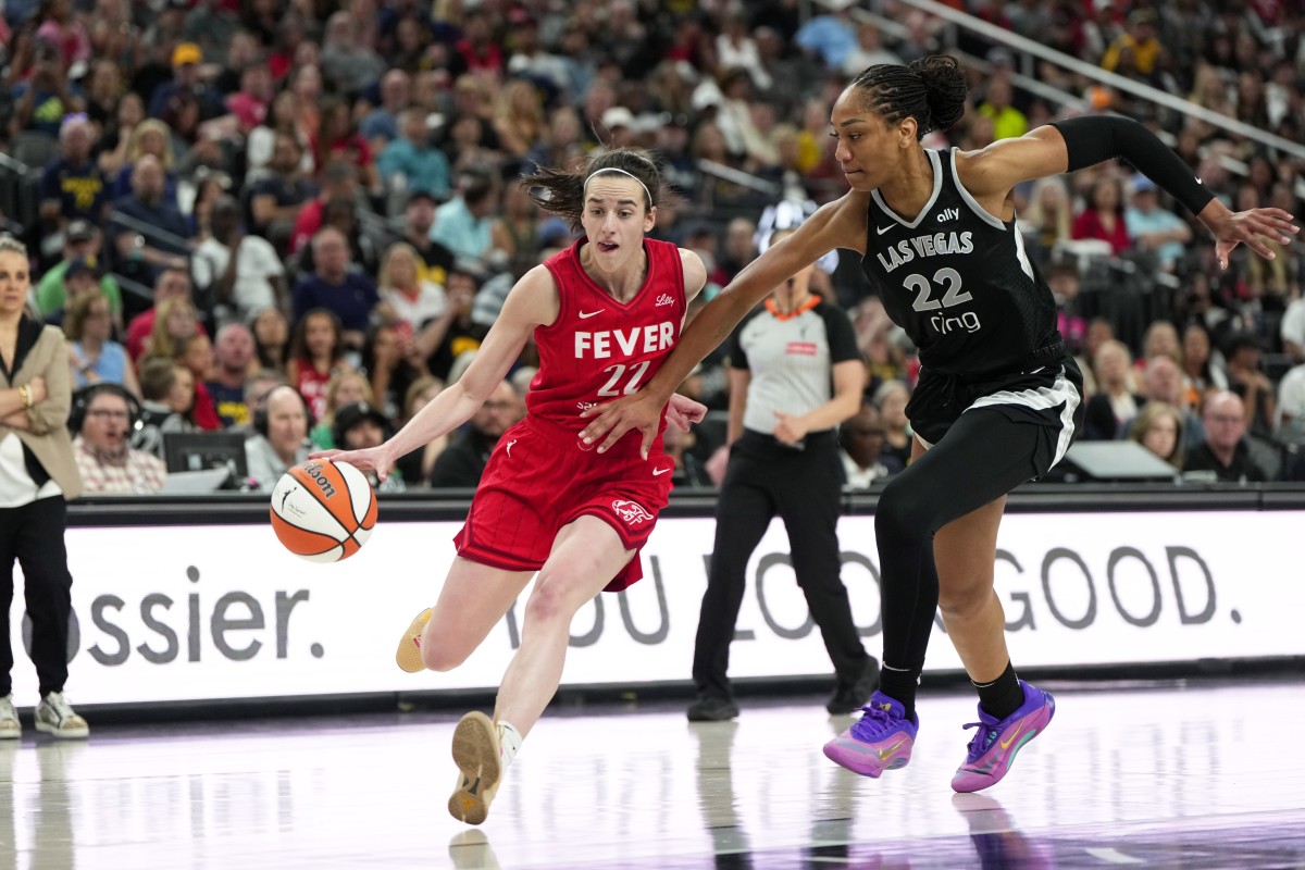 Indiana Fever guard Caitlin Clark (22) dribbles the ball against Las Vegas Aces center A'ja Wilson (22). 