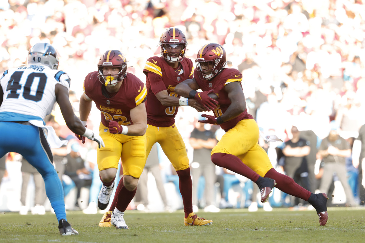 Washington Commanders quarterback Jayden Daniels (5) hands the ball to Commanders running back Brian Robinson Jr. (8) during the first quarter against the Carolina Panthers at Northwest Stadium.