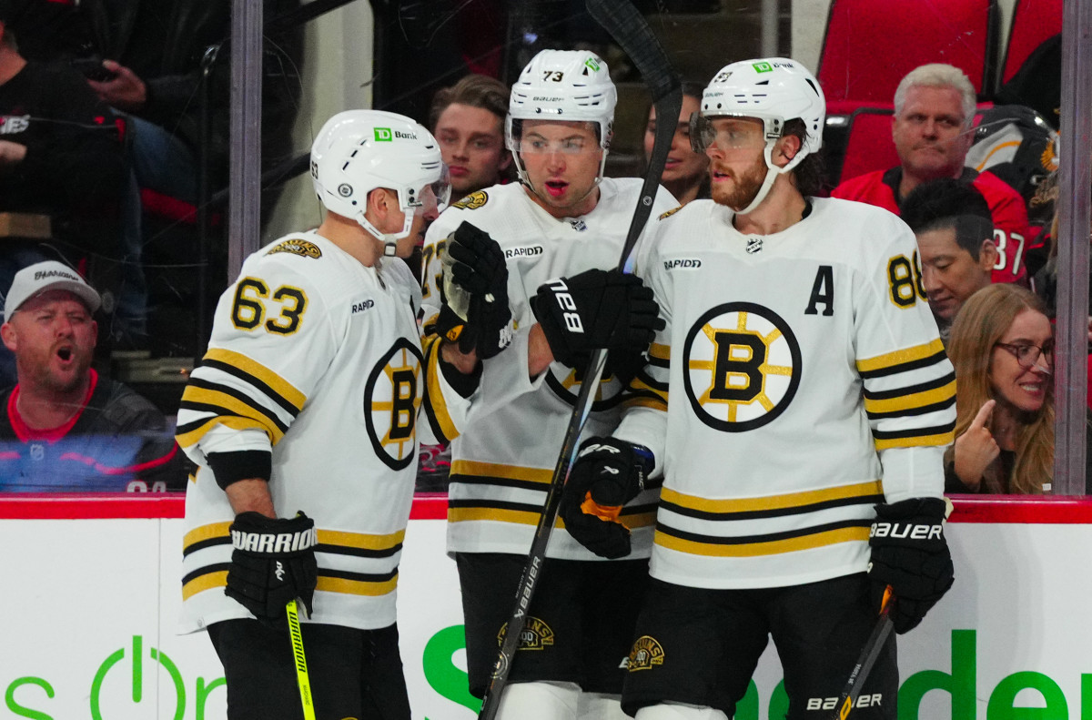 Boston Bruins left wing Brad Marchand (63) defenseman Charlie McAvoy (73) and right wing David Pastrnak (88) talk.