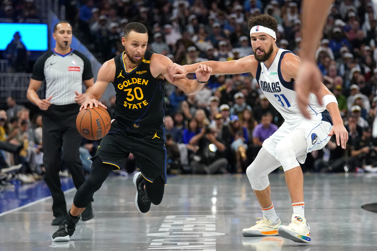 Golden State Warriors guard Stephen Curry dribbles past Dallas Mavericks guard Klay Thompson.