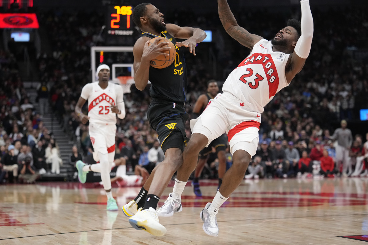 Jan 13, 2025; Toronto, Ontario, CAN; Toronto Raptors guard Jamal Shead (23) gets knocked over after colliding with Golden State Warriors forward Andrew Wiggins (22) during the second half at Scotiabank Arena. Mandatory Credit: John E. Sokolowski-Imagn Images