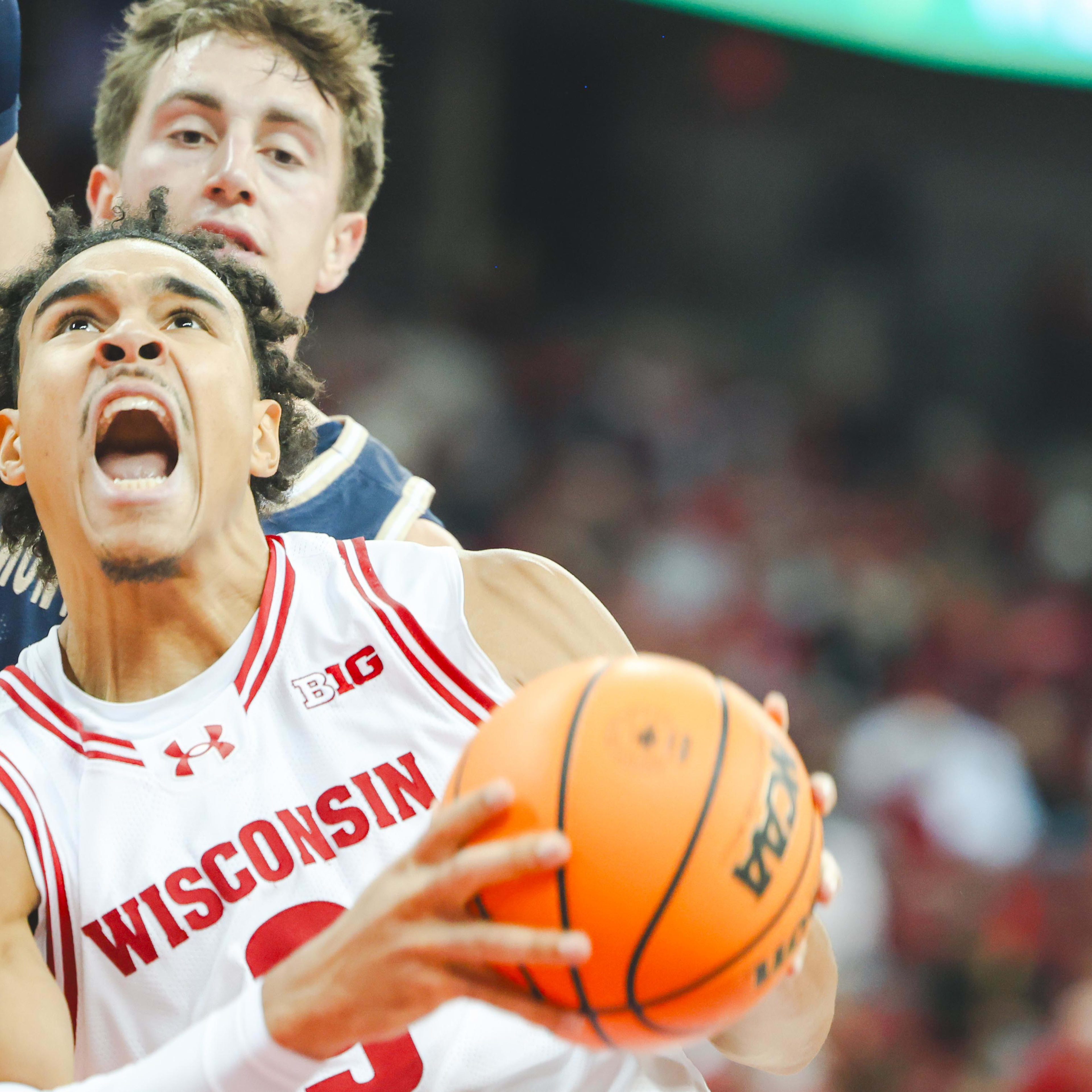 Wisconsin Badgers guard John Tonje makes an aggressive face with his mouth open in a close-up shot of him holding the ball while a Montana State defender is behind him.